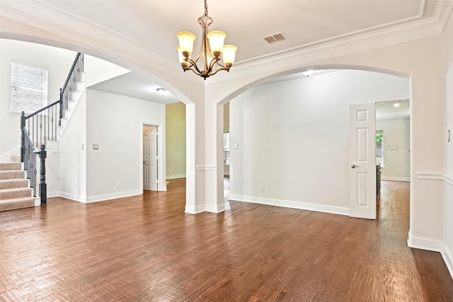 8604 Preston Wood Dr, Mckinney, TX 75072 - unfurnished living room with arched walkways, a chandelier, crown molding, dark wood-style floors, and stairs