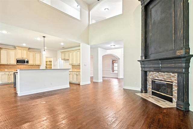 8604 Preston Wood Dr, Mckinney, TX 75072 - unfurnished living room featuring arched walkways, wood finished floors, a fireplace with flush hearth, baseboards, and recessed lighting