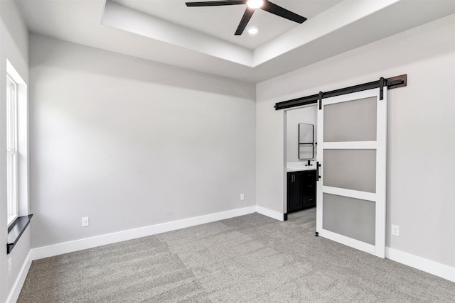 2519 Lakeridge Dr, Granbury, TX 76048 - unfurnished bedroom with a barn door, light colored carpet, a raised ceiling, baseboards, and recessed lighting