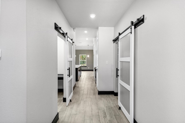 2519 Lakeridge Dr, Granbury, TX 76048 - hall featuring a barn door, recessed lighting, light wood-style floors, and baseboards