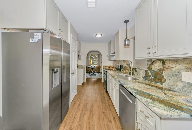 7616 Circle Dr, North Richland Hills, TX 76180 - kitchen with appliances with stainless steel finishes, a sink, arched walkways, light wood-style flooring, and tasteful backsplash