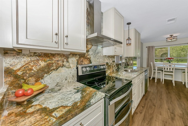 7616 Circle Dr, North Richland Hills, TX 76180 - kitchen featuring stainless steel appliances, wall chimney exhaust hood, a sink, wood finished floors, and backsplash
