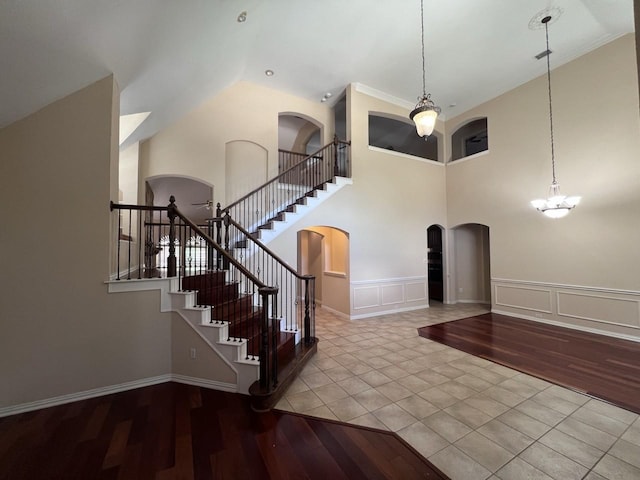 8205 Fountain Springs Dr, Plano, TX 75025 - stairway featuring arched walkways, wood finished floors, a decorative wall, a high ceiling, and a chandelier