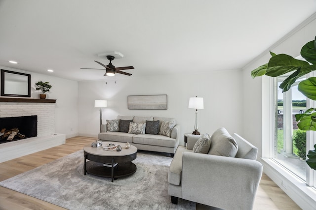 living area with wood finished floors, ceiling fan, a brick fireplace, and recessed lighting