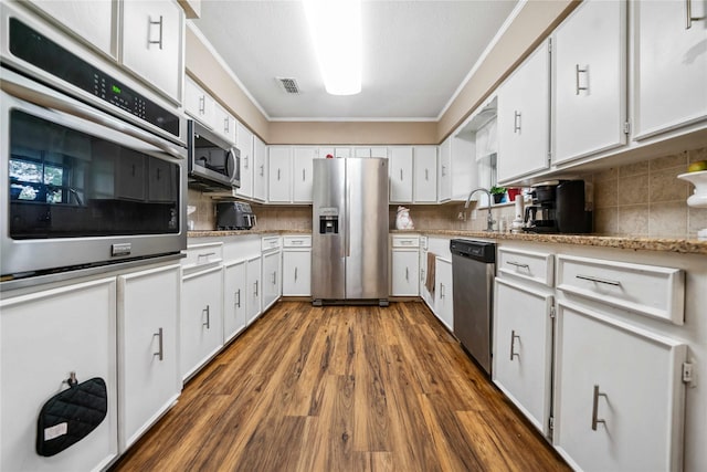 7223 Fm 2494, Athens, TX 75751 - kitchen with appliances with stainless steel finishes, decorative backsplash, dark wood-type flooring, ornamental molding, and white cabinetry