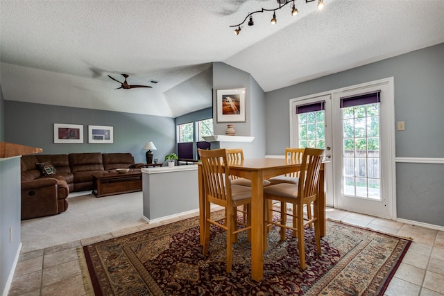 dining space with vaulted ceiling, a ceiling fan, a textured ceiling, and baseboards