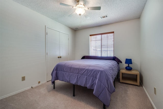 bedroom featuring a textured ceiling, carpet flooring, a closet, ceiling fan, and baseboards