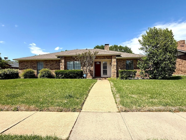 single story home with a front yard, brick siding, a chimney, and roof with shingles