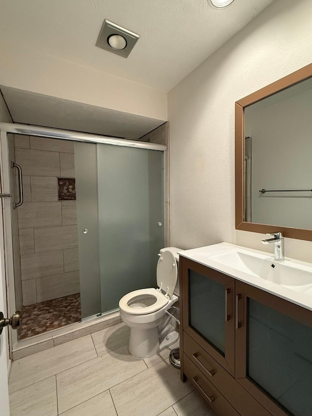 bathroom featuring a stall shower, toilet, and vanity