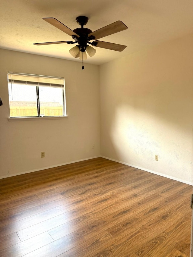 spare room with wood finished floors, ceiling fan, and baseboards