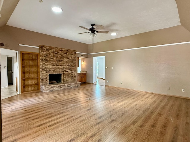 unfurnished living room featuring light wood-style flooring, a ceiling fan, a fireplace, lofted ceiling, and baseboards