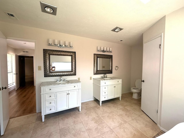 full bathroom featuring two vanities, tile patterned floors, toilet, and baseboards
