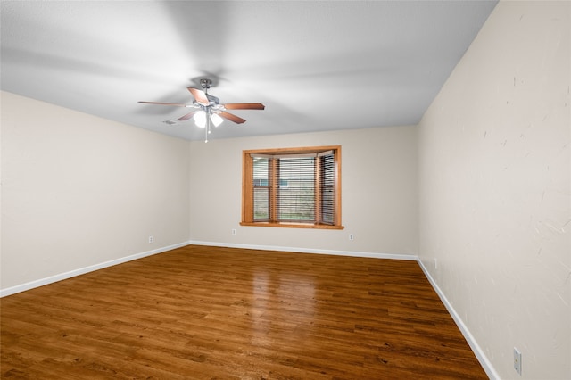 unfurnished room featuring a ceiling fan, wood finished floors, and baseboards