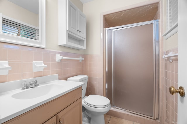 full bathroom with a stall shower, toilet, vanity, tile patterned flooring, and wainscoting
