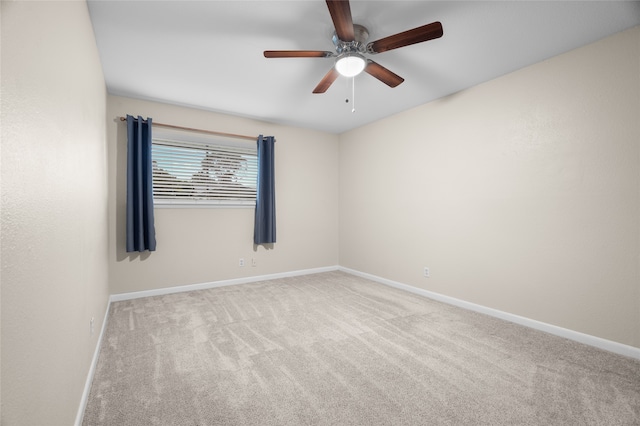 carpeted empty room featuring a ceiling fan and baseboards