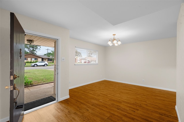 entryway with wood finished floors, a chandelier, and baseboards