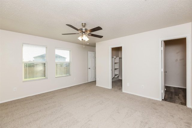 4913 Creek Ridge Trl, Fort Worth, TX 76179 - unfurnished bedroom featuring light colored carpet, a spacious closet, baseboards, a textured ceiling, and a ceiling fan