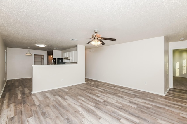 4913 Creek Ridge Trl, Fort Worth, TX 76179 - unfurnished living room featuring wood finished floors, a textured ceiling, a ceiling fan, and baseboards