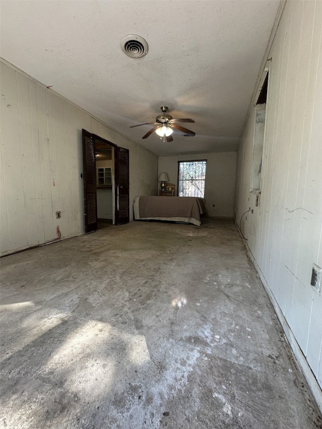 1505 Grove Dr, West Tawakoni, TX 75474 - unfurnished living room featuring ceiling fan, concrete floors, a textured ceiling, and wooden walls