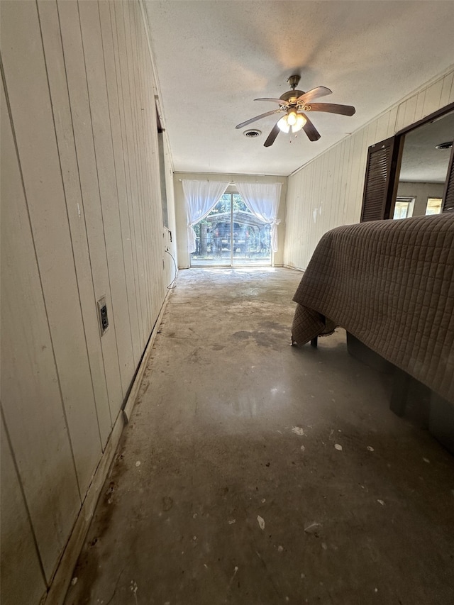 1505 Grove Dr, West Tawakoni, TX 75474 - bedroom featuring wooden walls, unfinished concrete floors, and a ceiling fan