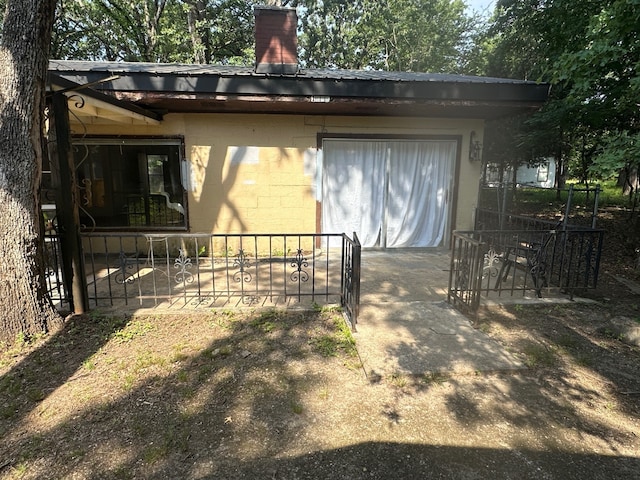 1505 Grove Dr, West Tawakoni, TX 75474 - view of home's exterior featuring concrete block siding, a chimney, fence, and a gate