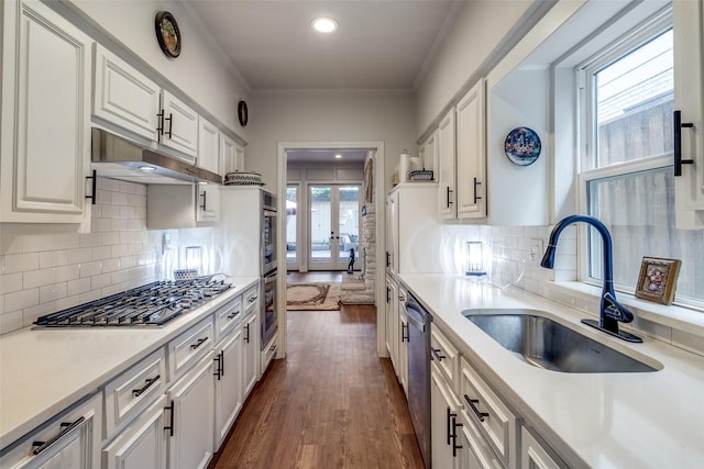 3552 Granada Ave Unit B, University Park, TX 75205 - kitchen with stainless steel appliances, a sink, under cabinet range hood, dark wood-style floors, and white cabinetry