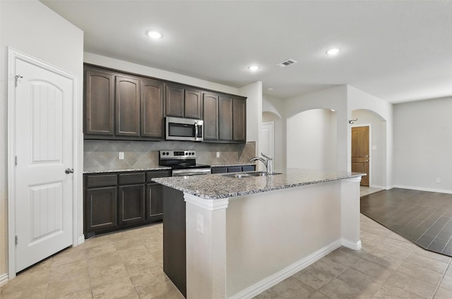 240 Springwood Ranch Loop, Springtown, TX 76082 - kitchen with stainless steel appliances, a sink, arched walkways, light stone counters, and decorative backsplash