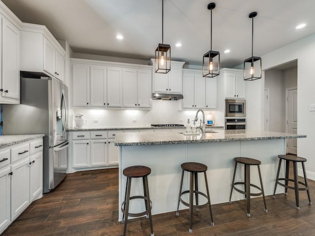 916 Timber Ridge Dr, Justin, TX 76247 - kitchen featuring stainless steel appliances, under cabinet range hood, dark wood-type flooring, white cabinets, and backsplash