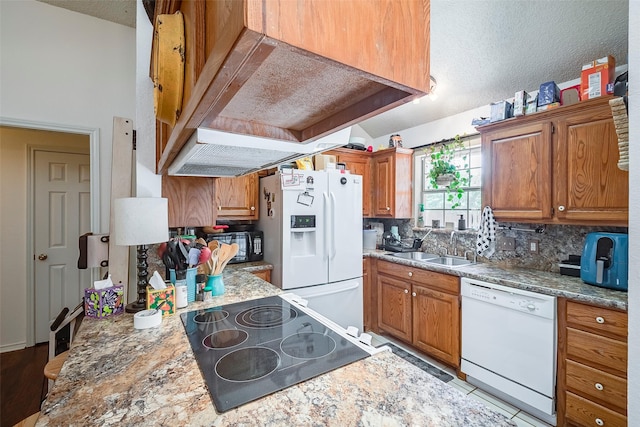 1112 Bayfield Dr, Denton, TX 76209 - kitchen with white appliances, wall chimney range hood, a textured ceiling, tasteful backsplash, and brown cabinets