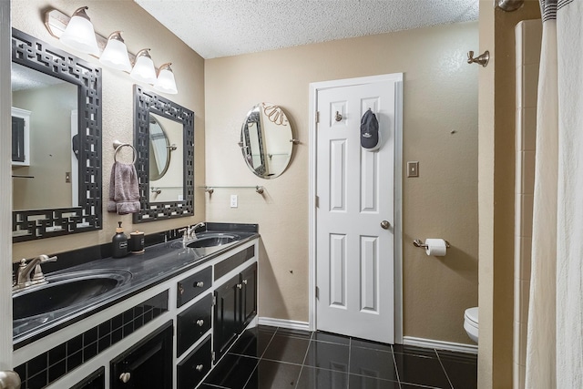 1112 Bayfield Dr, Denton, TX 76209 - bathroom with a textured ceiling, tile patterned floors, toilet, double vanity, and baseboards