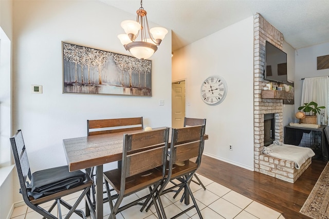 1112 Bayfield Dr, Denton, TX 76209 - dining area with a brick fireplace, baseboards, a chandelier, wood finished floors, and lofted ceiling