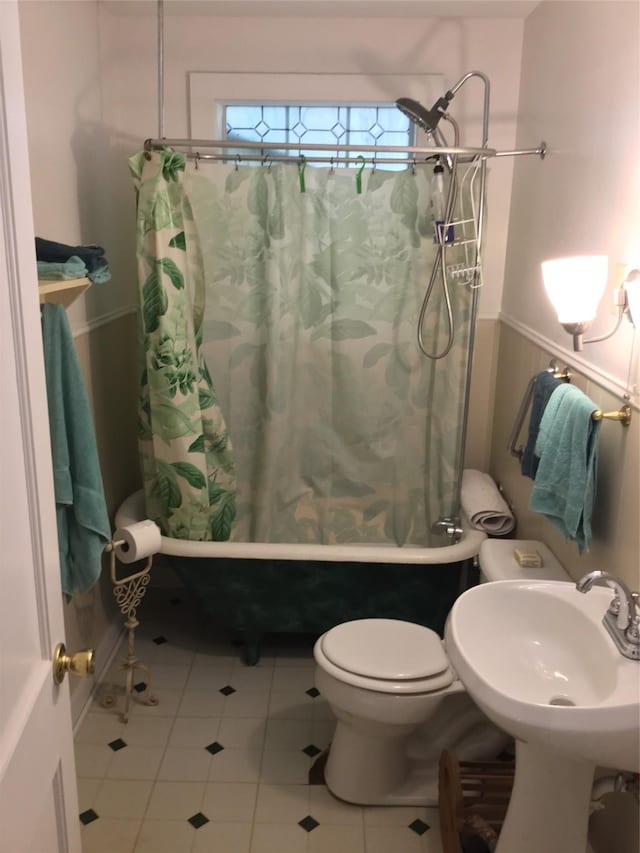 1014 N Sycamore St, Palestine, TX 75801 - full bath featuring tile patterned floors, shower / tub combo, toilet, a wainscoted wall, and a sink
