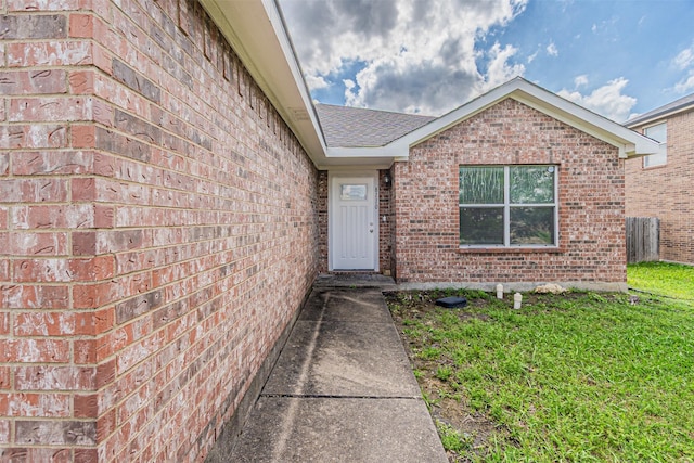 8110 Macgregor Dr, Arlington, TX 76002 - view of exterior entry with brick siding, a yard, and a shingled roof