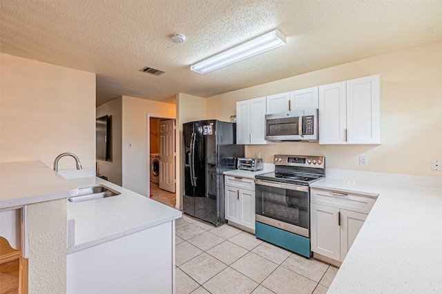 8110 Macgregor Dr, Arlington, TX 76002 - kitchen with appliances with stainless steel finishes, a sink, a peninsula, a textured ceiling, and white cabinets