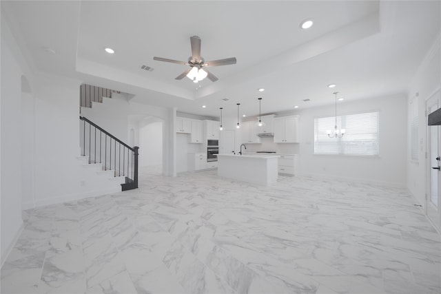 2301 Miramar Dr, Little Elm, TX 75068 - unfurnished living room featuring a tray ceiling, stairs, arched walkways, recessed lighting, and baseboards