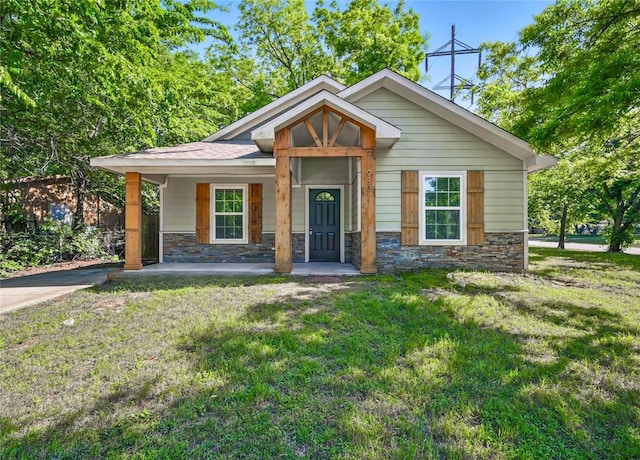 930 Baker St, Denison, TX 75020 - view of front facade featuring stone siding, a front yard, and covered porch