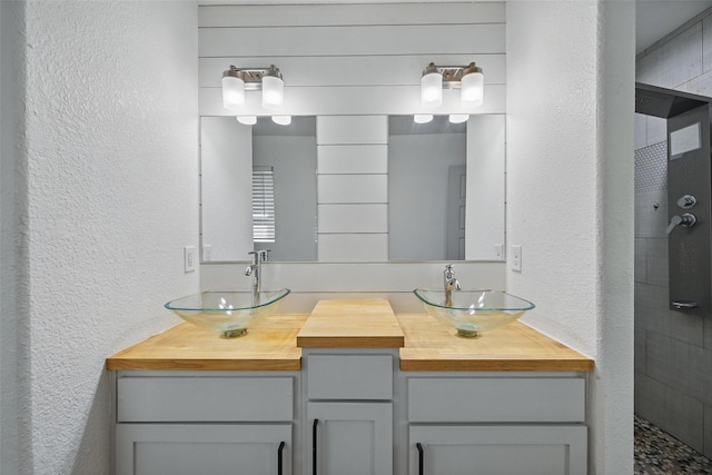 930 Baker St, Denison, TX 75020 - full bath with a textured wall, tiled shower, and double vanity