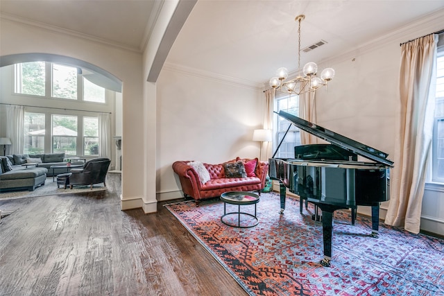 sitting room with wood finished floors, arched walkways, a chandelier, ornamental molding, and baseboards