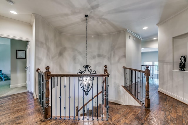 hall featuring an upstairs landing, wood finished floors, ornamental molding, a chandelier, and baseboards