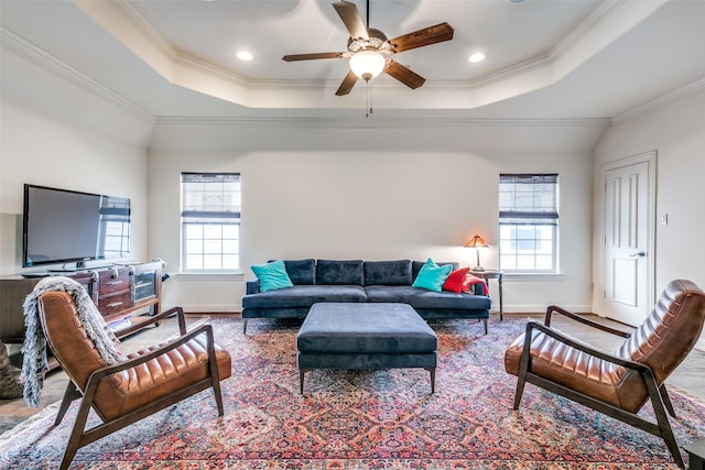 living area featuring crown molding, a raised ceiling, ceiling fan, baseboards, and recessed lighting