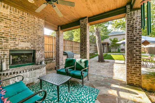 view of patio / terrace with an outdoor brick fireplace, a ceiling fan, and a fenced backyard