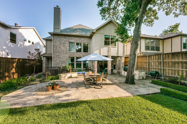 back of house with a patio area, a chimney, and brick siding