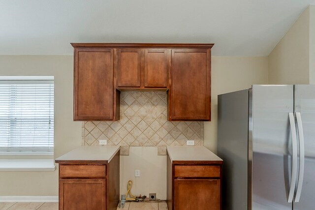 12113 Tacoma Ridge Dr, Fort Worth, TX 76244 - kitchen featuring freestanding refrigerator, tasteful backsplash, light countertops, brown cabinetry, and light tile patterned floors