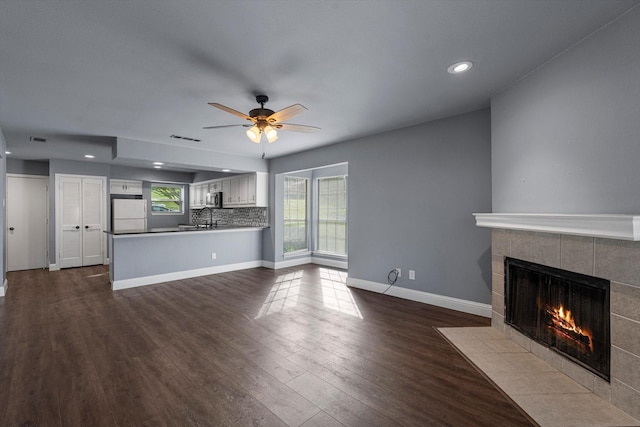 154 Henry M Chandler Dr, Rockwall, TX 75032 - unfurnished living room with a tiled fireplace, ceiling fan, dark wood-style flooring, recessed lighting, and baseboards