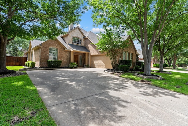 traditional-style home featuring brick siding, driveway, a garage, a shingled roof, and a chimney