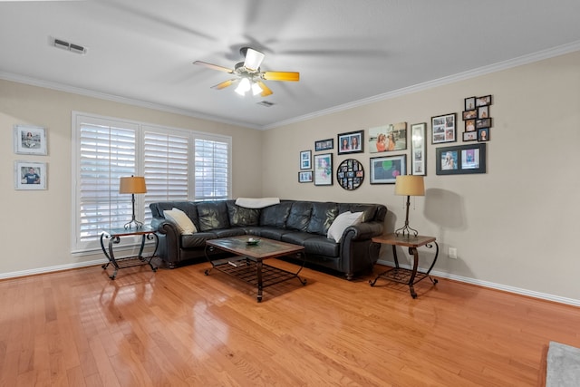 living room featuring light wood-style flooring, a ceiling fan, ornamental molding, and baseboards