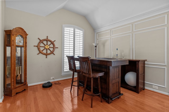 indoor dry bar with lofted ceiling, light wood-style floors, and baseboards