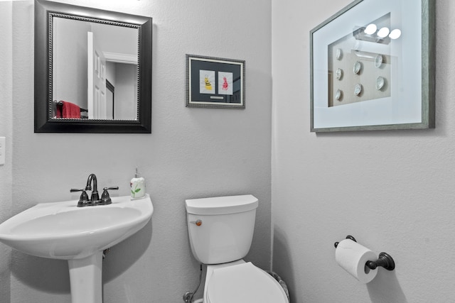 half bath featuring toilet and a sink