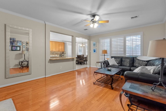 living room with a ceiling fan, light wood finished floors, ornamental molding, baseboards, and a chandelier