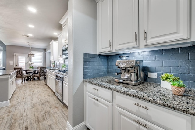 1912 Sunny Side Dr, Little Elm, TX 75068 - kitchen featuring white cabinetry, tasteful backsplash, stainless steel appliances, light wood-style floors, and light stone counters